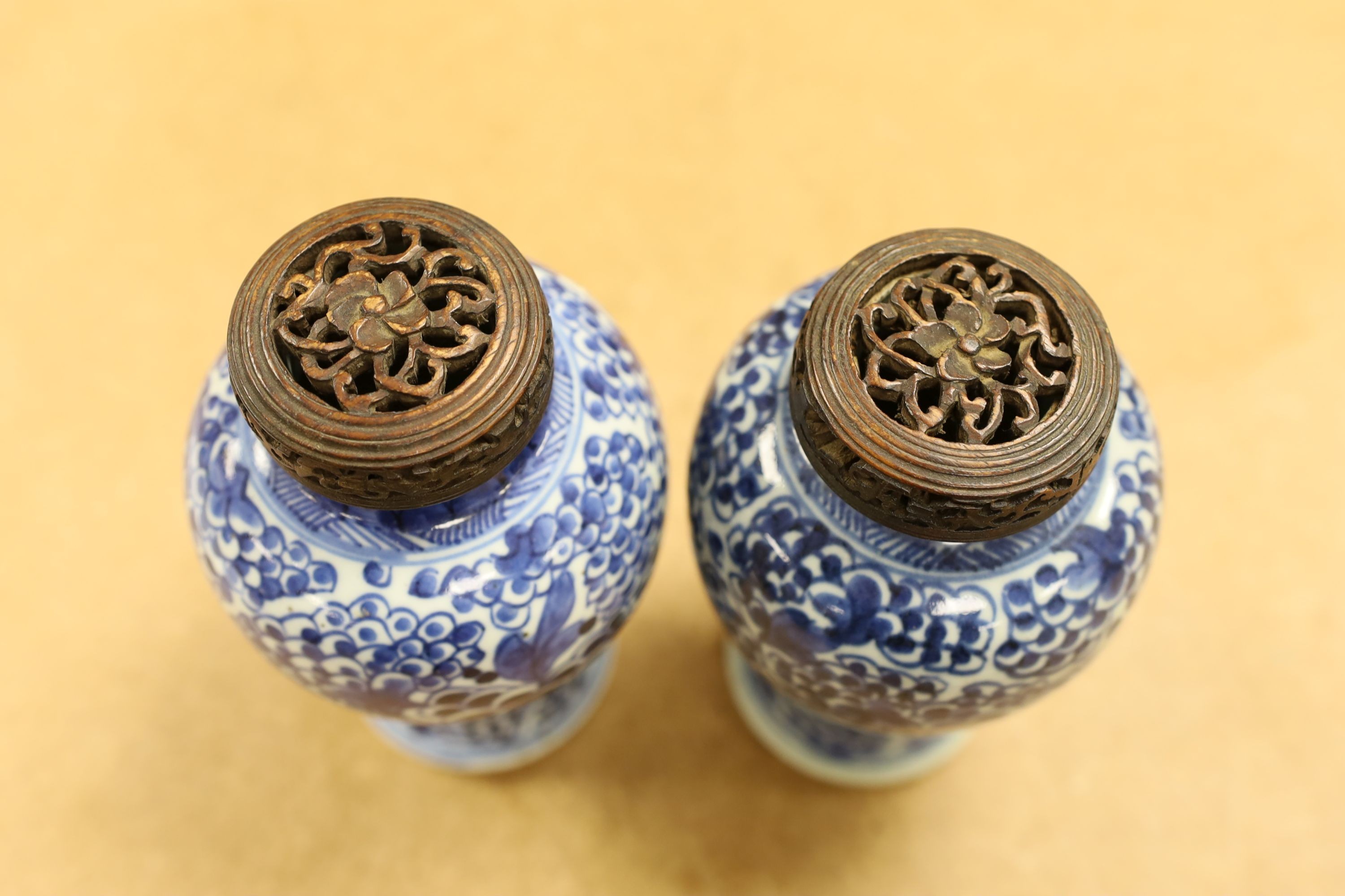A pair of Chinese blue and white 'phoenix' vases, Kangxi, associated wood covers, 19cm including covers